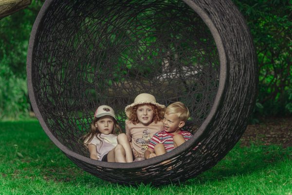 a group of kids sitting in a round black hanging chair